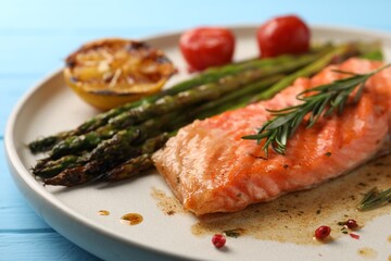 Tasty grilled salmon with asparagus and spices on plate, closeup
