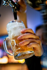 man bartender hand at beer tap pouring beer in glass in bar or pub