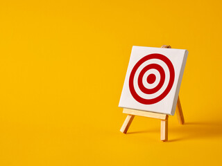 A canvas with target goal symbol on an easel with yellow background with copy space.