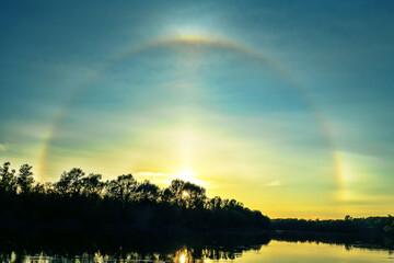 Unusual atmospheric phenomena. Very bright double halo (parhelic ring) over river at moment of evening sunset, windless spring day. Average flow of Don River. Mock sun with reflection in water