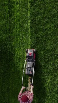 Professional worker with lawn mower mows the grass, top view