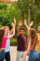 Cheerful excited multiethnic friends laugh out loud and give each other high five.