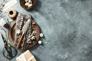 Easter table setting with spring flowers and cutlery on dark blue background top view flat lay