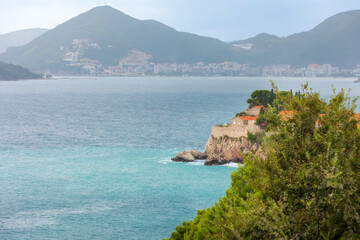 Sveti Stefan island in Montenegro resort at Adriatic sea and Budva skyline. High angle view. Famous travel destination