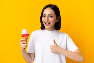 Young caucasian woman with a cornet ice cream isolated on yellow background with thumbs up because...