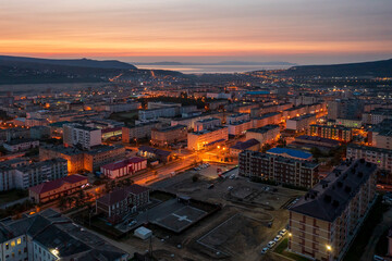 Morning aerial photograph of the city. Top view of the streets and buildings. Dawn. Empty streets and yards. In the distance the sea and hills. City of Magadan, Magadan region, Far East of Russia.