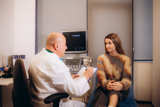Portrait of a doctor wearing stethoscope holding report file with appointment and giving consultation a smiling woman sitting on the couch in office during medical examination in clinic.