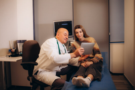 Portrait of a doctor wearing stethoscope holding report file with appointment and giving consultation a smiling woman sitting on the couch in office during medical examination in clinic.