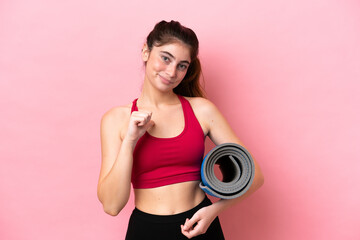 Young sport woman going to yoga classes while holding a mat proud and self-satisfied