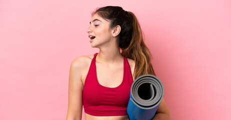 Young sport woman going to yoga classes while holding a mat laughing in lateral position