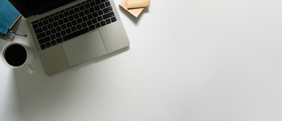 Laptop, cup of coffee and notebooks on white working desk. Flat lay, top view with copy space