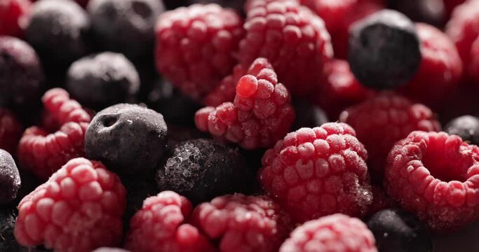 Close-up rotating frozen raspberries and blueberries background splash screen