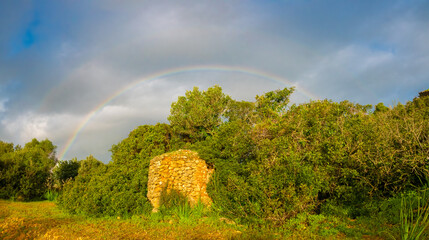 Double rainbow encircling the remains of a farm home in the Algarve region of Portugal