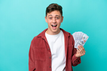 Young brazilian man taking a lot of money isolated on blue background with surprise facial...