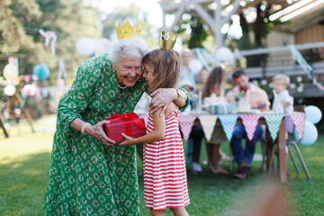 Garden birthday party for senior lady. Beautiful senior birthday woman receiving gift from...