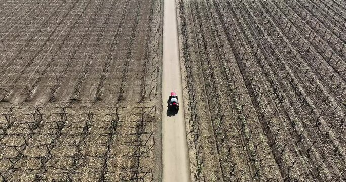 man farmer  driving red tractor on road between farms. path in middle of brown soil agriculture  feild