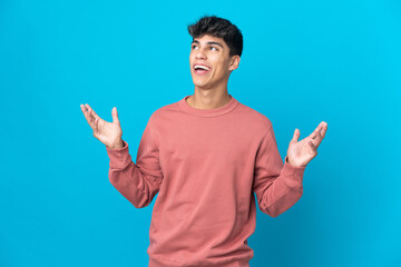 Young man over isolated blue background smiling a lot