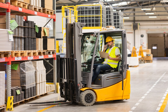 Warehouse forklift driver controlling shipping order. Warehouse worker preparing products for shipmennt, delivery, checking stock in warehouse, order picking.