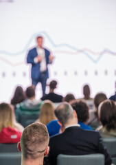 Blurred male speaker with presentation, in front of attentive audience in a conference or seminar...