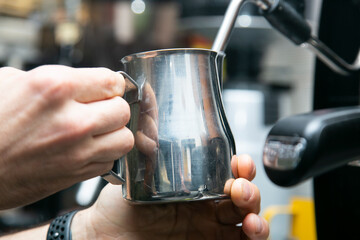 Professional barista working with a coffee machine and preparing hot drinks with coffee and milk.