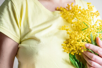young girl or woman holds yellow brunch of mimosa flowers. 8 march women's day concept.