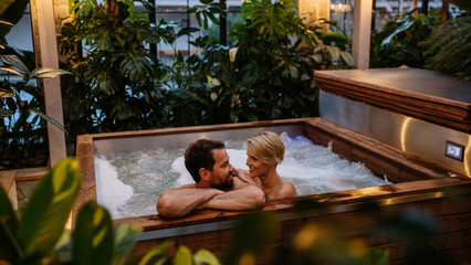 Beautiful mature couple relaxing in hot tub, enjoying romantic wellness weekend in spa. Concept of Valentine's Day. - obrazy, fototapety, plakaty
