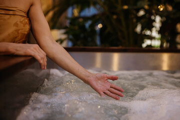Close up of woman standing by hot tub, splashing water, enjoying wellness weekend in spa.