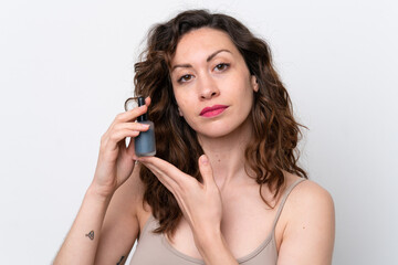 Young caucasian woman isolated on white background holding a serum. Close up portrait