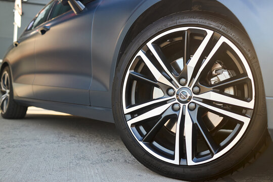 Berlin, Germany - August 20, 2022: third generation Volvo S60 detail shot. Volvo badges logo emblem on wheel plug and Kormoran Uhp 235 40 R19 96Y wheel selective focus close up.