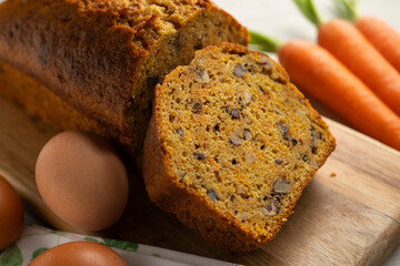 Delicious and fluffy carrot cake with walnuts on a wooden board.