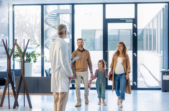Girl patient looking forward to her doctor and examination in a modern clinic. Girl arriving in hospital with her parents. Emotional support during medical examination.