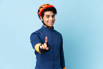 Venezuelan cyclist man isolated on blue background showing and lifting a finger