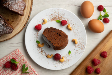 Fototapeta na wymiar Delicious and fluffy round chocolate cake with cashews and raspberries.