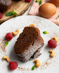 Delicious and fluffy round chocolate cake with cashews and raspberries.