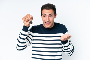 Fototapeta premium Young caucasian man holding home keys isolated on white background with shocked facial expression