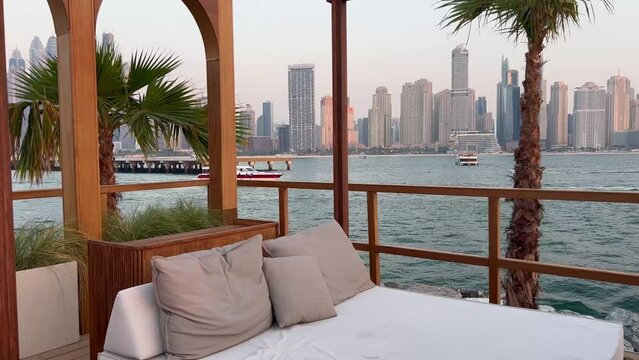 Dubai Jumeirah beach with marina skyscrapers in UAE. Luxurious sandy beach in the Dubai Marina area with views of the iconic skyscrapers. Beaches and Dubai eye view at sunset with boats and yachts.