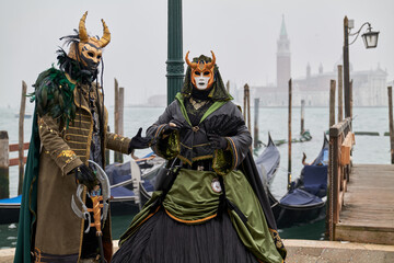 Fototapeta premium Venice, Italy - February 2024 - carnival masks are photographed with tourists in San Marco square