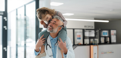 Portrait of a pediatrician with a little patient sitting on his shoulders, piggyback. Friendly...