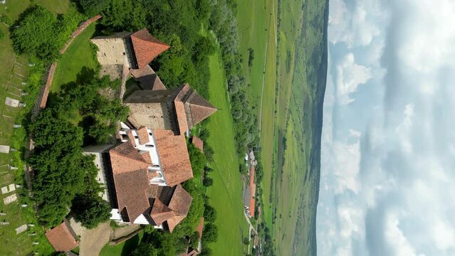 Beautiful and traditional Viscri Village. Viscri is only one of the Saxon villages of Transylvania. View of The Fortified Church and cemetery. Drone spinning around the church. Vertical footage