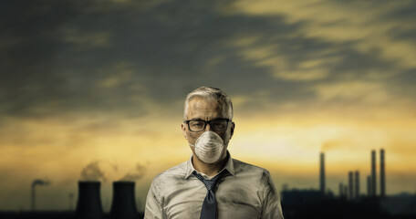 Businessman with face mask and polluting industrial plant