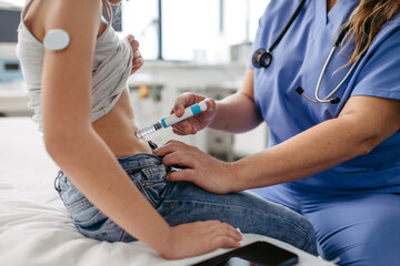 Nurse injecting insulin in diabetic girl belly. Close up of young girl with type 1 diabetes taking...