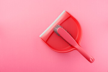 Pink plastic dustpan and brush on pink background
