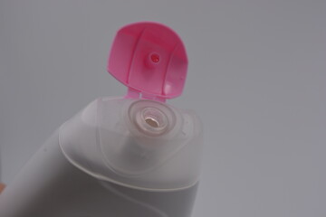 Women's cosmetics, care products, shower gel in white plastic bottle with pink cap placed on white background.