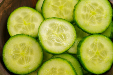 Fresh cucumber slices in a wooden bowl. Vegetable salad ingredients