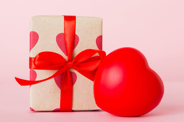 gift box with red bow and red heart on colored background. Perspective view. Flat lay