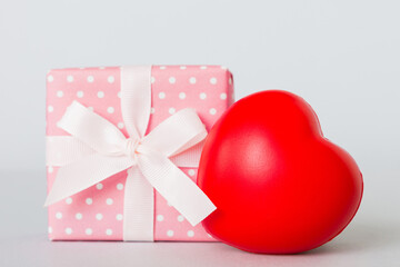 gift box with red bow and red heart on colored background. Perspective view. Flat lay