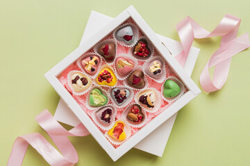 Holiday composition: sweet candy, with gift boxes with bow and chocolate hearts, photo template, background. Top View with copy space on colored background