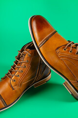A pair of premium calfskin boots on a green background. Vertical shot.