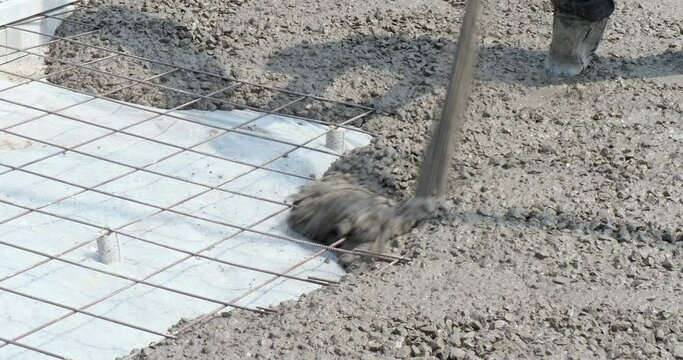Close up of concrete pouring directly on the ground and reinforced with steel rebars