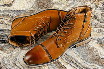 A pair of premium calfskin boots on a stone background. Horizontal shot.